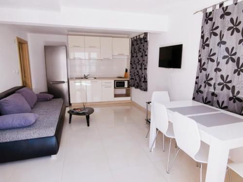 een woonkamer met een bank en een tafel en een keuken bij Apartment Jurčević in Trogir
