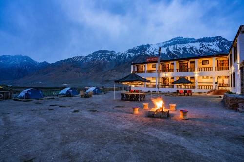 a building with tents and a fire in front of it at Zostel Spiti in Kaza