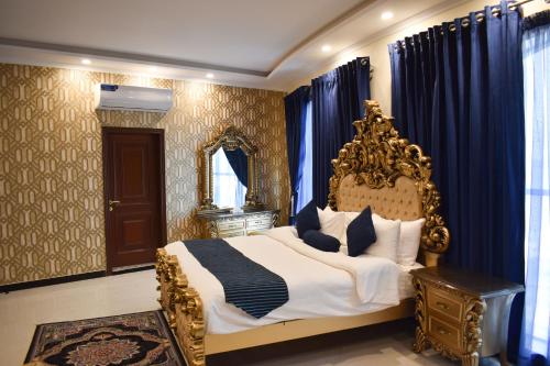 a bedroom with a king sized bed with blue curtains at Hotel de Raj Sialkot in Sialkot