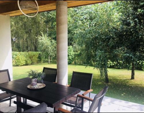 a table and chairs on a patio with a view of a yard at House on the edge of forest by Zalew Sulejowski in Swolszewice Duże