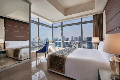 a hotel room with a bed and a desk with a view at The Residences of The Ritz-Carlton Jakarta Pacific Place in Jakarta