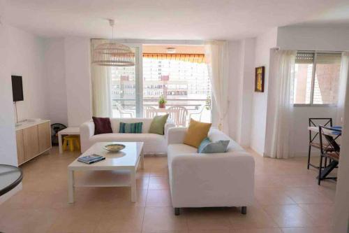 uma sala de estar com um sofá branco e uma mesa em Gran apartamento, Aire acondicionado, piscina y parking gratuito em Alicante