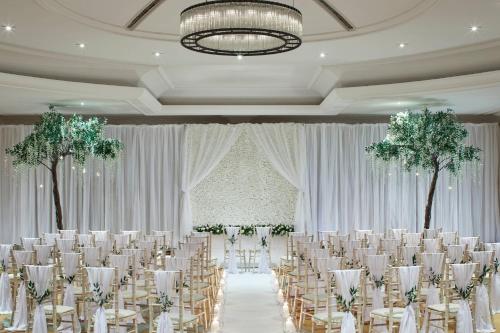 a banquet hall with tables and chairs and trees at Delta Hotels by Marriott St Pierre Country Club in Chepstow