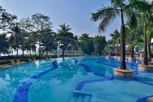 a large swimming pool with palm trees in a park at The Westin Mumbai Powai Lake in Mumbai