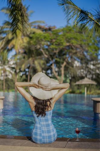 a woman wearing a hat sitting in front of a pool at The Westin Mumbai Powai Lake in Mumbai