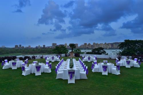 un gruppo di tavoli e sedie bianchi su un campo di The Westin Mumbai Powai Lake a Mumbai