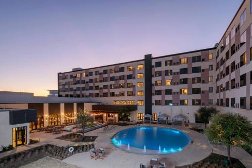 a hotel with a swimming pool in front of a building at Marriott Dallas Allen Hotel & Convention Center in Allen