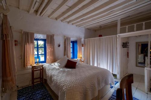 a bedroom with a bed with a white comforter and windows at Authentic Bodrum House in Bodrum City