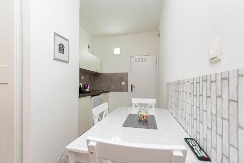a white kitchen with a white table and chairs at Apartments Stipe in Lokva Rogoznica