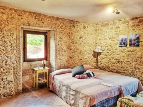 a bedroom with a bed in a room with stone walls at Alojamiento Casa Carlota in Villadesuso