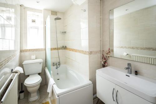 a white bathroom with a toilet and a sink at Cosy 3BD London accommodation for 6 / 6 beds in London