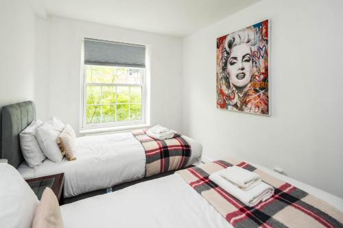 two beds in a white room with a picture on the wall at Cosy 3BD London accommodation for 6 / 6 beds in London