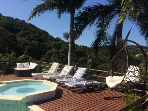 a group of chairs and a pool on a deck at Pousada Mar'Tito Forno in Búzios