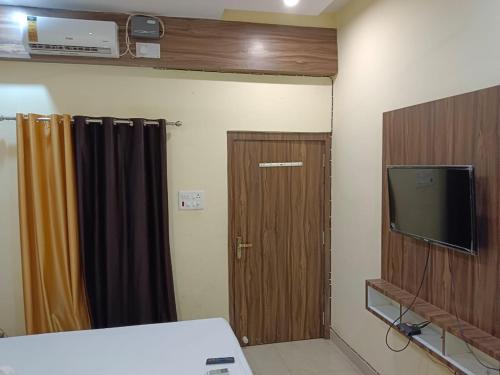 a room with a wooden door and a television at The A Cube Inn in Bokāro