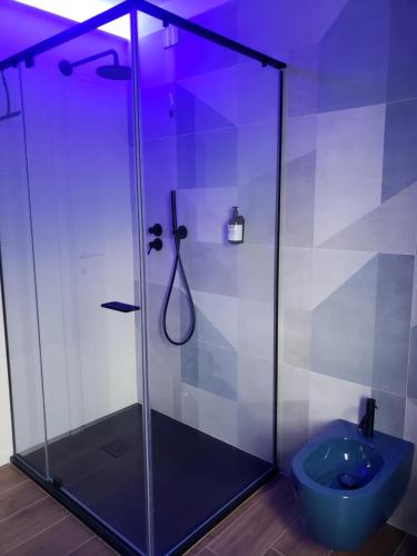 y baño con ducha de cristal y aseo azul. en Vinomare Guesthouse en Fosdinovo