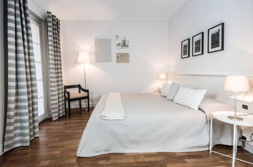 a white bedroom with a white bed and a chair at Golf Hotel Castelconturbia in Agrate Conturbia