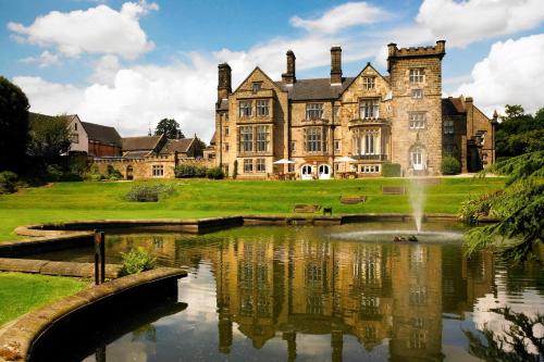 a large castle with a pond in front of it at Delta Hotels by Marriott Breadsall Priory Country Club in Derby
