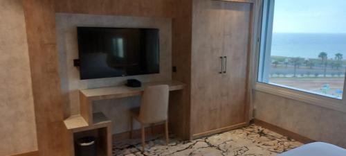 a room with a television and a chair and a window at فندق حياة تاون 2 in Umm Lujj