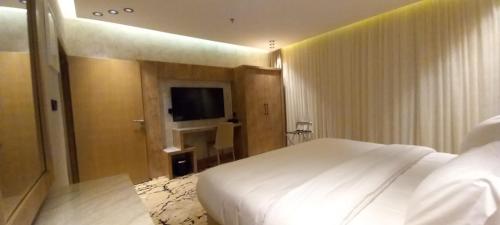 a bedroom with a white bed and a television at فندق حياة تاون 2 in Umm Lujj