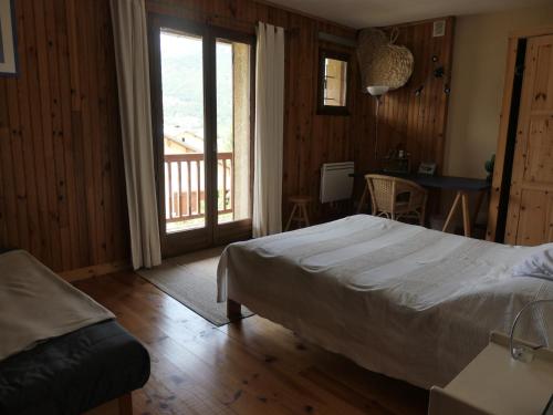 een slaapkamer met een bed en uitzicht op een balkon bij Le Ginkgo - Mont Dauphin in Eygliers