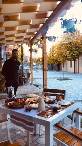 Un uomo in piedi accanto a un tavolo con del cibo sopra. di Te Cemi - Restorant - Hotel a Tamarë