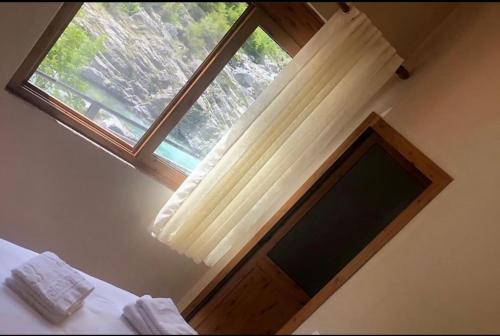 ventana en un dormitorio con cama y cortina en Te Cemi - Restorant - Hotel, en Tamarë
