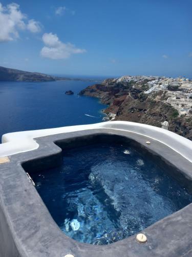 a hot tub with a view of the ocean at Captain John Oia Cave Houses-Sunset,Volcano & Caldera Views in Oia