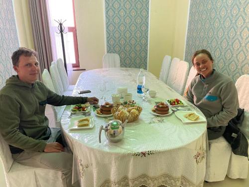 a man and a woman sitting at a table with food at Muras in Bokonbayevo