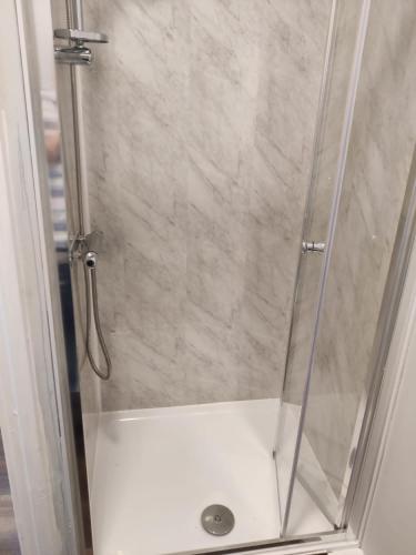 a shower stall with a glass door with a shower at Nice and Pleasant in Thornton Heath