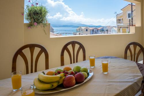 a plate of fruit on a table with orange juice at A&S Seaside House in Lixouri