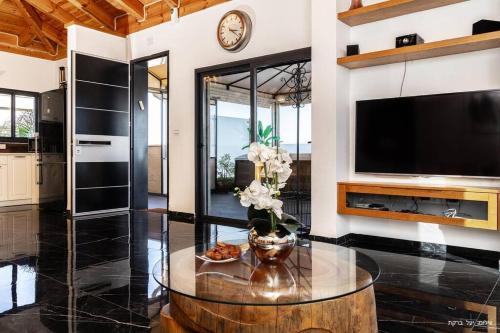a living room with a large television and a table at מאיורי בוטיק - וילה מקסימה עם בריכה פרטית ונוף מהמם למשפחות בלבד in Mishmār Hāyardin