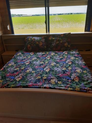 uma cama com um edredão floral e almofadas em De Bizon em Warmenhuizen