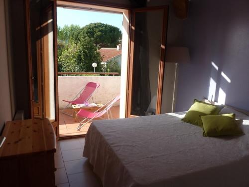 - une chambre avec un lit et un balcon avec une chaise dans l'établissement Appartement 2 pièces avec terrasse dans une petite résidence à 150m de la plage, à Saint-Cyr-sur-Mer