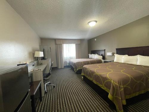 a hotel room with two beds and a flat screen tv at DuPont Suites - Louisville - St. Matthews in Louisville