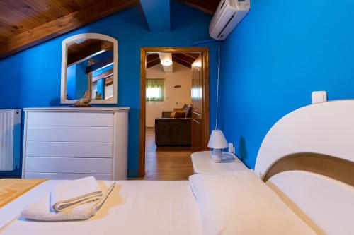 una camera blu con un letto bianco e uno specchio di A&S Seaside Maisonette a Lixouri