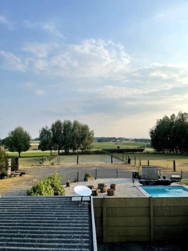 a patio with a pool and a table and a chair at La maison des chevaux in Maulde