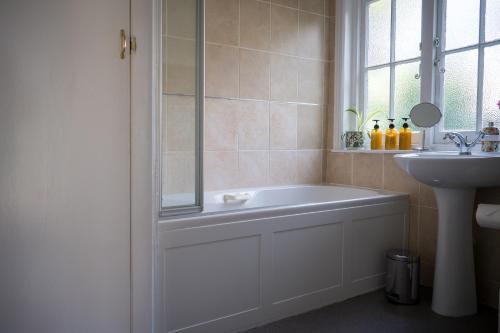 a bathroom with a bath tub and a sink at Birdsong & Pine: parking & garden in Worthing