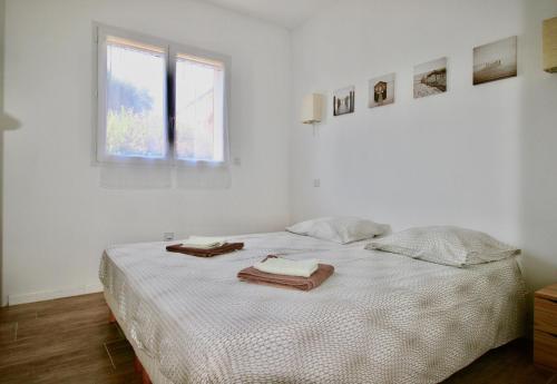 a white bedroom with a bed with towels on it at Appartements avec jardin entre Porto-Vecchio et Figari - Casa Mattiste in Sotta