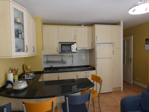 une cuisine avec des armoires blanches et un comptoir noir dans l'établissement Appartement proche de la mer et du port Pays Basque Hendaye, à Hendaye