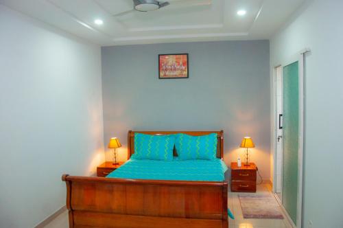 a bedroom with a bed with blue sheets and two lamps at Résidences 509 in Lomé