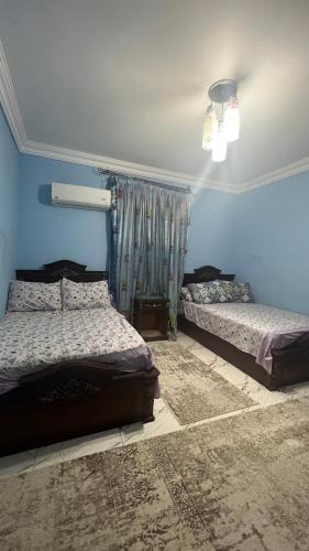 een slaapkamer met 2 bedden en een blauwe muur bij شقه للايجار بمدينه نصر in Caïro