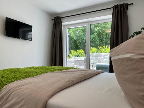1 dormitorio con 1 cama, TV y ventana en EXCLUSIVES APARTMENT - Auszeit Mondsee en Mondsee