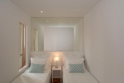 a white bedroom with two beds and a lamp at Bolhão Nobre Apartments in Porto