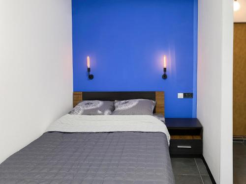 a bed with a blue wall and two lights on it at Urban Home in Kyiv