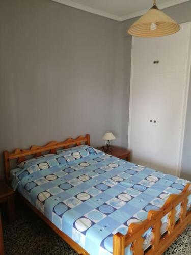 a bedroom with a wooden bed with a blue comforter at 50 metres from the beach in Hanioti