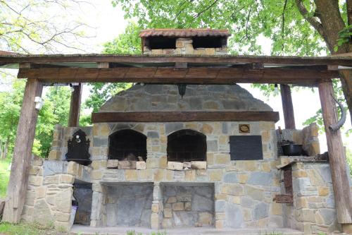 an outdoor brick oven with a wooden roof at Садиба У Романа 'корпус із сауною' in Verkhneye Sinevidnoye