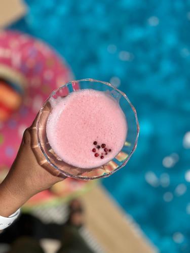 a hand holding a glass with a pink drink at Pupa Alaçatı Butik Otel in Cesme