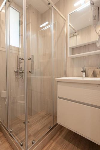 a bathroom with a glass shower and a sink at Bukovo Apartment - Hellenic Apartments Avlona in Oinófita