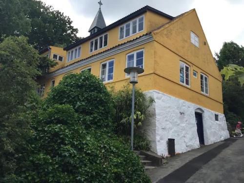 a yellow building with a tower on top of it at CHARMING FARM HOUSE IN GUDHJEM in Gudhjem