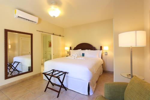 a bedroom with a large white bed and a mirror at Bungalows at Windsong on the Reef in The Bight Settlements